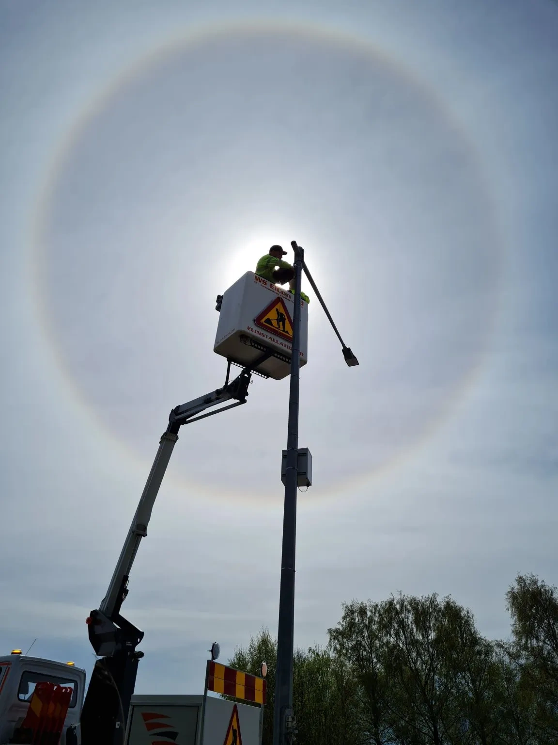 Traffic worker in a crane fixing a lamp.