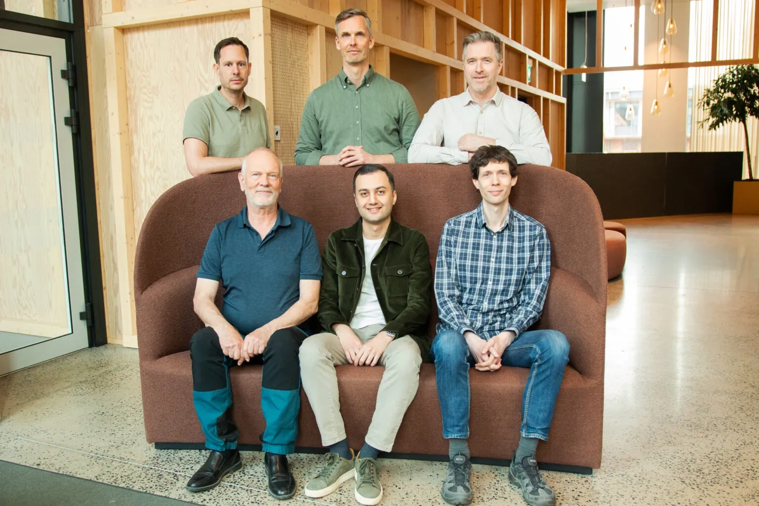 Team Xense - three people sitting on a red sofa, three people standing behind.